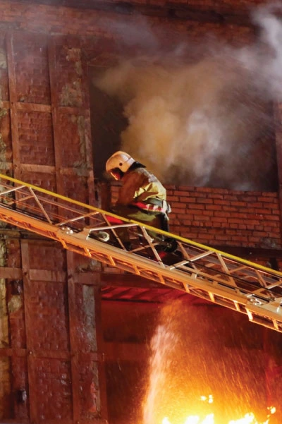 a firefighter on a ladder next to a building on fire